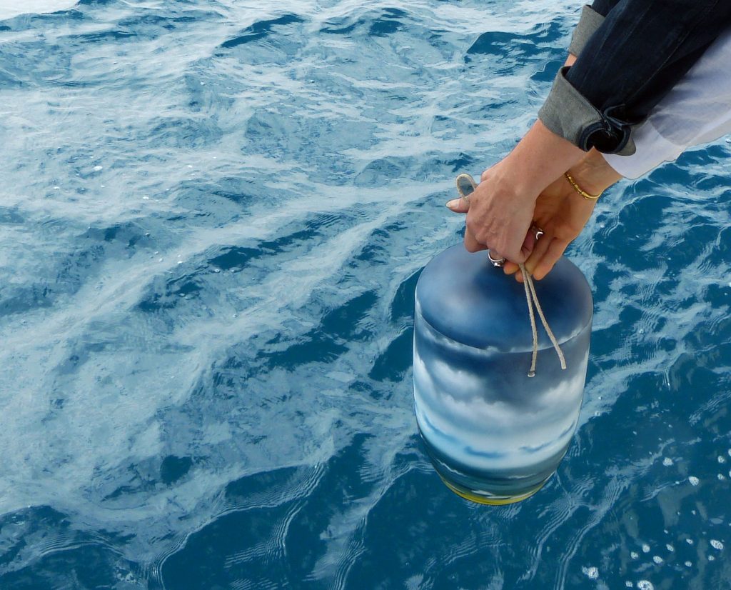 Eine Seeurne wird von den Angehörigen bei einer Seebestattung vor Mallorca ins Meer gegeben